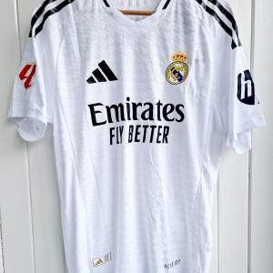 Säljer Real Madrids matchtröja för kommande säsong 2024/25 med Bellingham på ryggen. Tröjan är en reprint i nyskick med emblem och patchar av högsta kvalité. Tröjan är en player version. Tajt i storleken. 