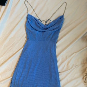 Blå glittrig klänning  - Blå glittrig klänning med öppen rygg med snören, detaljer där bak.