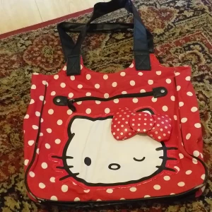 Röd Hello Kitty handväska - En röd handväska med vita prickar och en stor Hello Kitty-design på framsidan. Väskan har svarta handtag och en stor röd rosett med vita prickar.                                                                     Jag kör frakt eller träff i Stockholm/ Botkyrka Titta på mina andra annonser,  samfraktar gärna :)
