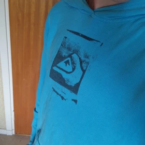Ljusblå Hoodie - En Ljusblå Hoodie med en cool design på fram och backsidan. Stor ingen storlek men den passar mig och jag är storlek M