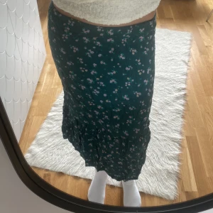Mörkgrön långkjol  - Kjolen är mörkgrön med blommönster. Den är från H&M  💕