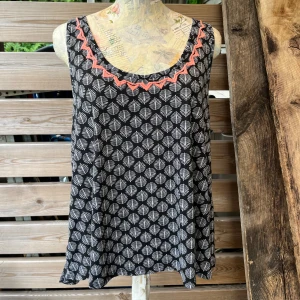 Härligt linne stl M - Super härligt linne stl M, lite vidare modell med djupare v-ringning bak, slitsar i sidorna och brodyr framtill. Knappt använt i fint skick! Marinblått med vitt mönster och aprikos/orange brodyr