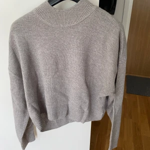 Grå tröja  - Oanvänd, normal i storlek men kortare i modellen. 