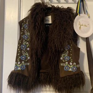 Hippie väst med blomdekorationer - Superhäftig väst med blomdetaljer och päls! Från Urban outfiters, storlek medium. Går lika bra att stänga den med spännen, eller att ha öppen! <3