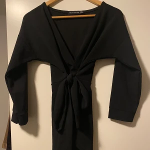 Svart Blus - En svart blus från prettylittlething s 38. Köpt för ett tag sen men användt Max 1-3 gånger. Den är v ringad och en snörning runt midjan. Köpt för runt 300kr och säljer för 120kr. Den är i väldigt bra skick då den inte kommit till så mycket användning