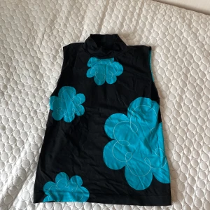 Svart tröja med blå blommor -  Snugg Svart tröja med blå blommor köpt från humana