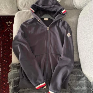 Moncler Zip  - Säljer nu min moncler zip. Den är i okej skick, liten defekt på ärmen som visas samt lite solblekt. Givetvis äkta, skriv vid frågor!