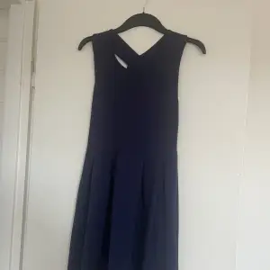 En fin klänning med en öppen rygg som ser ut som ett kryss. Jätte fin marinblå färg. Knappt använd. 