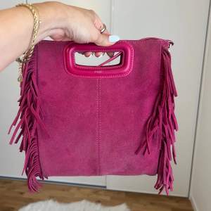 En rosa maje väska, man får med ett långt band men går att ta bort det bandet:)