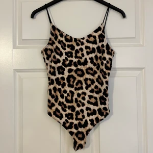 Body med knappar  - En leopard mönstrad body med öppen rygg som aldrig är använd.