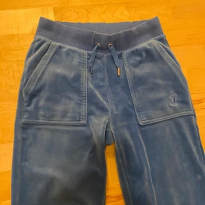 Blå Juicy Cotoure byxor  - Fina blå Juicybyxor i storlek XXS💙De är lite uppsydda i benen men passar mig perfekt som är 167,5 cm lång. En av ”topparna” på snöret har lossnat men limmas på innan jag skickar dem. Lite slitna runt knän och hälar. Kontakta för mer info 😊