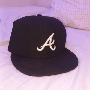 Atlanta Hawks Fitted Cap - En snygg fitted baseball cap. Loggan på kepsen är laget Atlanta Hawks Logga. Kepsen är svart och Har storleken 54,9cm/6⅞. Kepsen är tvättad på högvärme i maskin för att undika löss. Köpt för 449kr. Pris kan diskuteras.