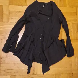 Assymetrisk svart skjorta med många knappar. Längre framtill, pirat-vibe och perfekt med korsett eller skärp. Okej att komma med egna bud. Katt i hemmet. 