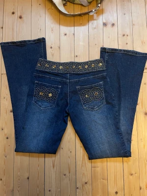 SÅ SNYGGA LÅGMIDJADE JEANS!!! - Supercoola lågmidjade bootcut jeans med paljetter både på fickorna och på linningen. Aldrig använda av mig så de är i helt perfekt skick. 