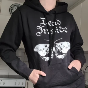 Svart hoodie - Svart hoodie "Dead Inside" tryck med en mal. Står storlek XL men är mer som en XS/S. Aldrig använd, nypris: 699:-.  Kom med prisförslag 😊  Material: 80% Bomull, 20% Polyester. 