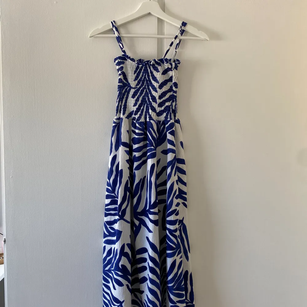 Säljer denna söta blå blommiga klänning, perfekt till sommaren. I storleken XXS. Från HM. Kan även användas som en långkjol. Inga defekter, använd en gång🙌🏻💕. Klänningar.