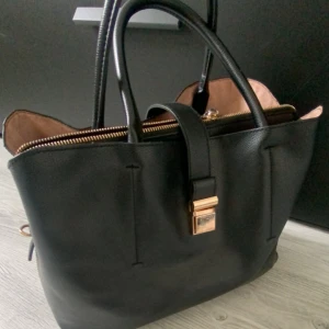 Väska - Fin svart väska med guld detaljer som man får plats saker i, den har tre stora fack😇