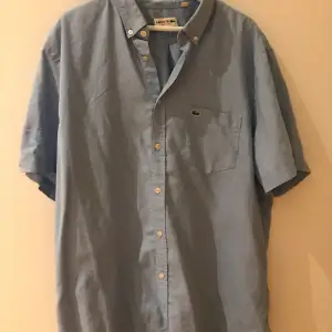 Klassisk kortärmad lacosteskjorta i linne/polyester som är väldigt skön på sommaren. Jag har L men har haft den oversized men passar även upp till 2XL. Bra skick!