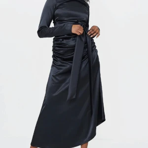 Svart satin festklänning från Prettylittlething - Jättefin klänning från Prettylittlething som är helt slutsåld. Den har fortfarande sitt etikett och är oanvänd. Behöver tyvärr sälja den för att storleken passar inte mig