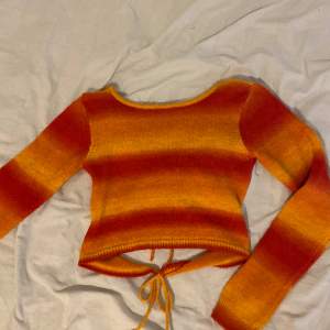 Orange/röd tröja med knytning från urban outfitters. Man kan ha den på båda hållen. Stickad, bra kvalité. Endast använd 1 gång.