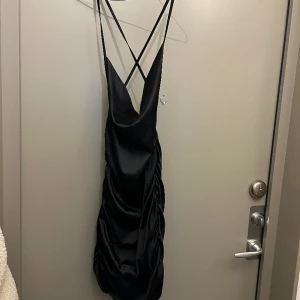 Satin klänning - Oanvänd svart satinklänning med öppen rygg. Dragkedja på baksidan av klänningen