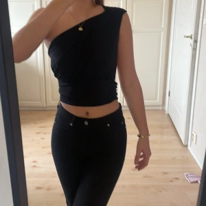 Fest topp - Svart fest topp från nakd Hanna schönbergs kollektion, superfin som går över ena axeln och öppen i ryggen. Varför jag säljer den är för att den är lite stor för mig annars sitter den bra! 