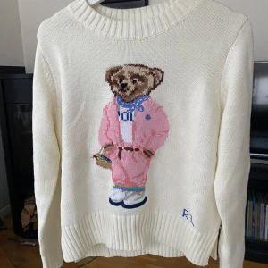 Ralph Lauren Polo Bear Stickad Tröja - Ralph Lauren Stickad Sweatshirt med Rosa Polo Bear. Cream/Vit färg & Storlek S. Köpte som present till min syster men passade inte. Helt ny, endast testad. Nypris runt 4000kr