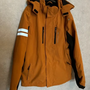Lindberg jacka  - En fin jacka från Lindberg (15K performance). Jackan är hel och i bra skick. Är vattentät och varmt vadderad,och fodrad i mjuk fleece. Är Brun/orange färg 