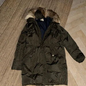 Dunjacka från Lampelius  - Fin lampeliusjacka i grönt med avtagbar päls. Jag säljer den pågrund av att jag har för många jackor och behöver bli av med några. Den är i superfint skick, de ända felet är att två snören till luvan har lossnat. Nypris 8-9 tusen 