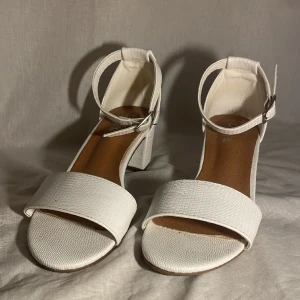 Vita klackskor  - Säljer dessa superfina vita klackskor ifrån ”Duffy” då de inte används. De är i storlek 39 och är näst intill i nyskick då de bara används 1-2 gånger. 