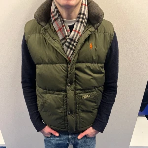 Ralph Lauren Dunväst - Stilig väst med märket Ralph Lauren. Modellen är 175 och sitter perfekt. Cond på västen är 8,5/10. Tveka inte på att höra av dig vid minsta funderingar😁