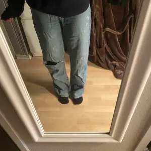 Högmidjade jeans med hål över ena knät 
