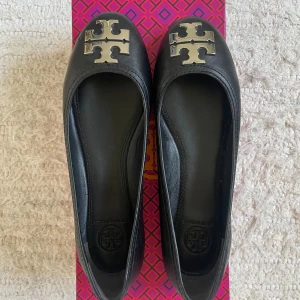 Svarta ballerinaskor med metallogo - Snygga och bekväma Tory Burch ballerina skor i svart läder. Perfekt för vardagligt bruk eller för att klä upp sig lite extra!