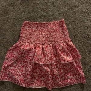 Blommig kjol - En volang kjol med rosa blommor och inbyggda shorts. Märket är okänt men köpt på Plick. Mycket bra skick. Passar Xxs-s