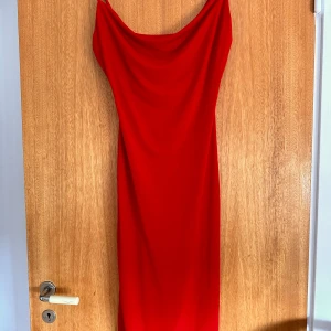 Midiklänning  - Midiklänning i vacker röd färg. Den har elastisk tyg och vattenfallsringning.   Sparsamt använd. 