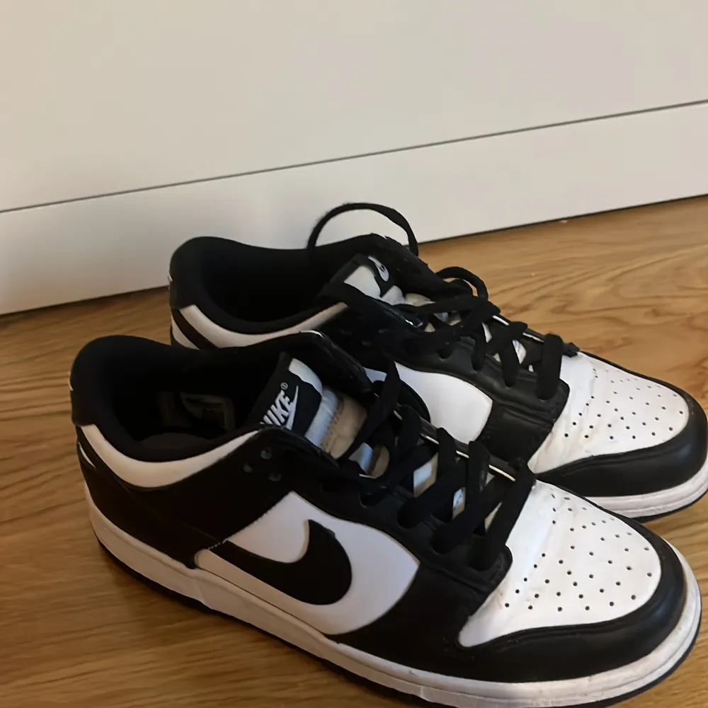 Säljer ett par snygga svartvita Nike Dunk sneakers. De är i bra skick dock lite cresade, har en klassisk design med svart och vitt läder. Perfekta för både vardag och fest! Skorna har snörning och en bekväm passform.. Skor.