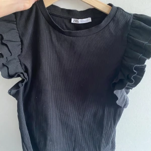 Zara topp - Säljer en ribbad volangtopp från zara i storlek L. Den är dock liten i storlek så den sitter bra på mig som vanligtvis bär s. I bra skick använd 2-3gånger. 