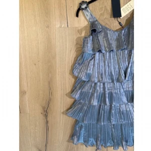 NY Nyårsklänning från Muse storlek S - helt ny klänning från märket Muse med lapparna kvar! silvrig klänning med volagner. perfekt till nyår :)  kan mötas upp i uppsala eller stockholm annars står köpare för frakt!