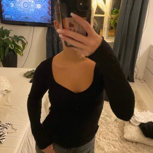 Svart långärmad topp - En svart långärmad topp från Nelly med detalj vid bröstet💗storlek xs