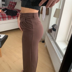 Bruna kostymbyxor  - Långa bruna kostymbyxor, rak passform. Spännet är trasigt som blivit ersatt med säkerhetsnål, kan skicka bilder. Därav billigare pris!❤️