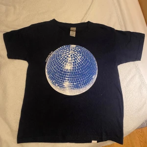 Jättesnygg Blå t-shirt - Jag säljer min T-shirt som är marinblå med en diskokula, för att den inte kommer till användning 💙Jag har bara provat den men inte använt. Ny pris:350kr säljer för 200kr+ frakt, det är storlek S men skulle säga att den också passar XS💙