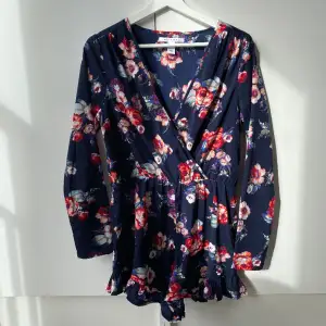 Söt mörk blommig playsuit från Nelly Trend.  Volanger nedtill. Stretchig i midjan. Tunt material.  Använd en del, i gott skick. 