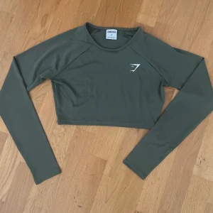 Gymshark cropped träningströja - Olivgrön cropped träningströja från Gymshark i storlek XS, som ny. 🌟