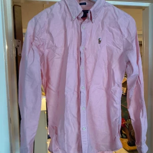 Ralph lauren skjorta - Rosa Ralph lauren skjorta i 100%ull size 10(passar s-m) slim fit. Perfekt till soliga o varma dagar och är tvättad en gång. Säljer på grund av att den blivit för liten för mig. Om ni har frågor hör av er.
