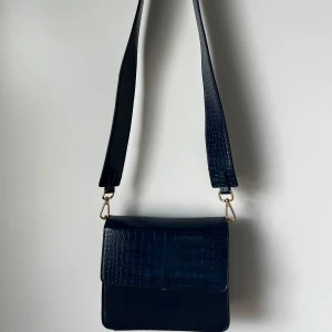 Tjockrems väska  - Kommer med 2 olika typer av väskband. Har ett par svarta märken på baksidan av väskan som inte riktigt går bort. 