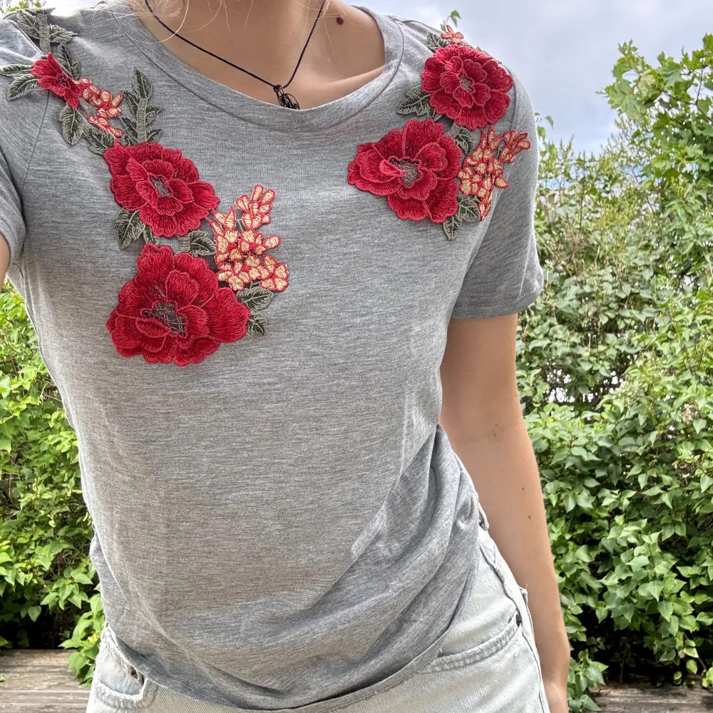 Grå t-shirt med påsydda, broderade blommor samt blad från TopShop. Bara använd 2-3 gånger! Storlek: 36. Material: 50% bomull + 50% modal. :). Toppar.