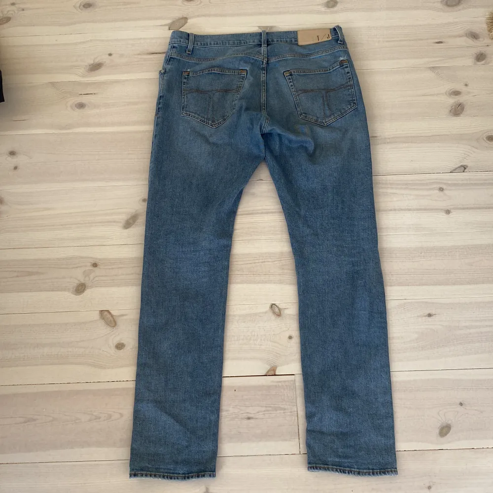 Blåa Tiger of Sweden jeans i storlek 33/34. Litet hål vid bakfickan, se bild 2.. Farkut & Housut.