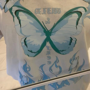 Vit t-shirt  - En fin tröja men en blå fjäril och text på fram sidan. Tröjan ligger i bra skick. Original pris 120kr. 💖💖