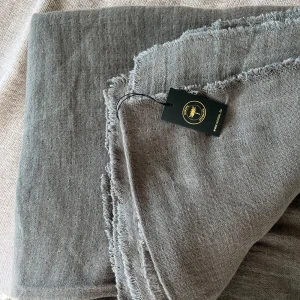 Nordal yoga sjal/filt bomull olivgrön - Ny, oanvänd yoga sjal/filt från Nordal. Gjord av naturmaterial i en blandning av bomull och linne (75% bomull, 25% linne). 160x140 cm. Används för mysiga stunder och när det är svalt, till före/efter t.ex yoga eller under t.ex meditation. Olivgrön.