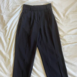 Svarta kostymbyxor - Snygga kostymbyxor med metallknäppen på insidan. Lösa i passformen 